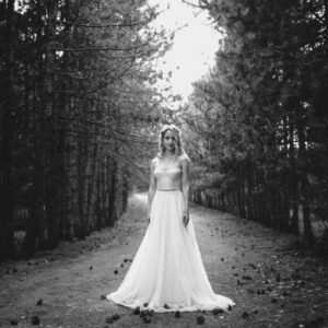 Ethereal bride facing the camera wearing a bohemian dress and flower headdress during an artistic photoshoot | https://milenkovikweddings.com/